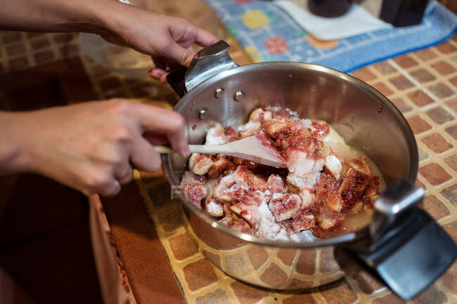De cima da colheita pessoa anônima com espátula misturando pedaços de figo frescos com açúcar no fogão enquanto prepara o engarrafamento na cozinha — Fotografia de Stock