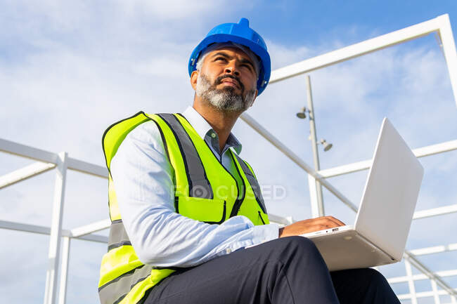 De baixo supervisor masculino em uniforme trabalhando em netbook sentado perto da central solar — Fotografia de Stock