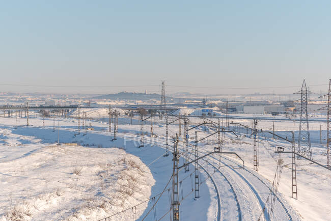 Drone vista del treno su ferrovia su terreno innevato sotto cielo blu chiaro — Foto stock