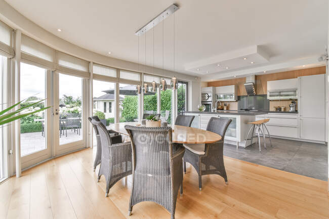 Kreative Gestaltung von Esszimmer und Küche mit Sesseln und Tisch unter Lampen, die zu Hause an der Fensterwand hängen — Stockfoto