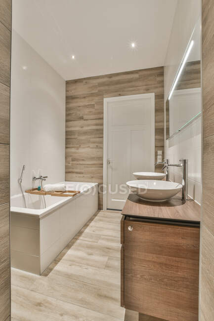Prateleira de madeira na banheira no banheiro moderno com paredes de azulejos — Fotografia de Stock