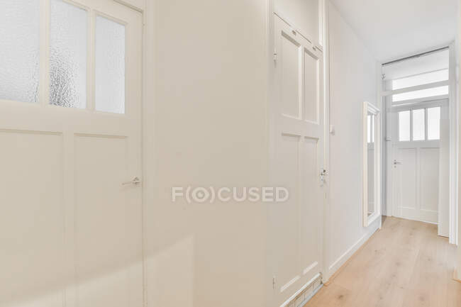 Интерьер коридора со светлыми дверями и стенами в стиле минимализма в современной квартире — стоковое фото