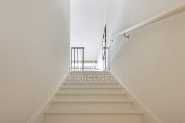 Diseño creativo de escalera entre paredes ligeras con barandilla y valla bajo techo en casa - foto de stock