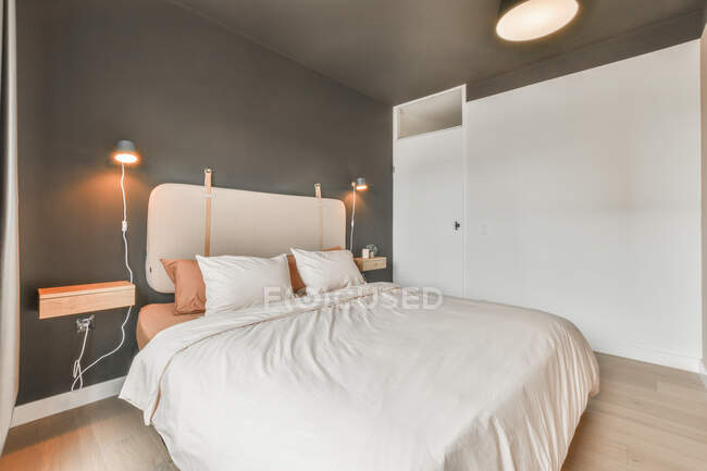 Bequemes Bett mit heller Bettwäsche im stilvollen Schlafzimmer tagsüber — Stockfoto