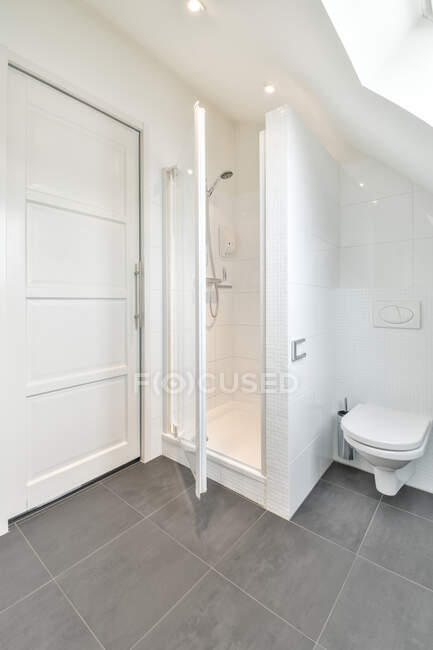 Design creativo del bagno con wc contro doccia e porta in casa con pavimento in ceramica grigia — Foto stock