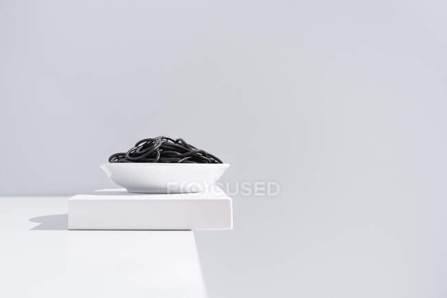 Minimalistisches Atelier mit Spaghetti mit schwarzer Tintenfischtinte in voller Keramikschale auf weißem Tisch — Stockfoto