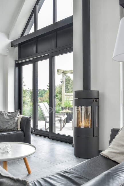 Интерьер стильной просторной гостиной серого цвета с удобными диванами возле стеклянных дверей — стоковое фото