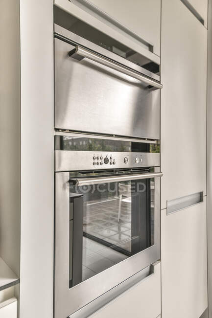 Construído em microondas e forno com painel de controle contra geladeira na cozinha contemporânea em casa — Fotografia de Stock
