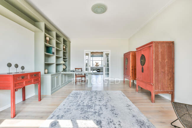 Интерьер просторной светлой комнаты с деревянными шкафами и встроенными полками с декорациями возле стола и стула — стоковое фото