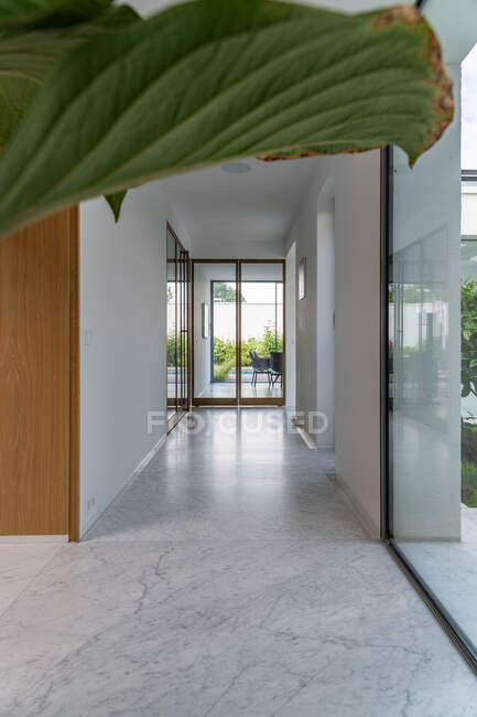 Spacieux couloir lumineux avec sol en marbre et murs blancs dans une villa résidentielle moderne par temps ensoleillé — Photo de stock