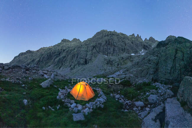 Malerischer Blick auf Zelt auf Moos mit Steinen vor schroffem Berg unter blauem Himmel in der Dämmerung — Stockfoto