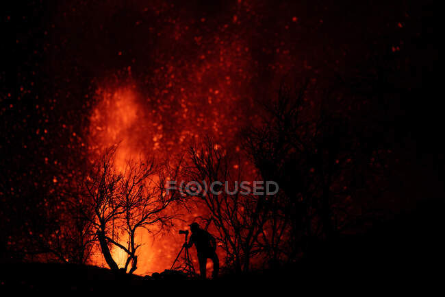 Silhouette eines Fotografen gegen explodierende Lava und Magma, die aus dem Krater strömen. Cumbre Vieja Vulkanausbruch auf La Palma Kanarische Inseln, Spanien 2021 — Stockfoto