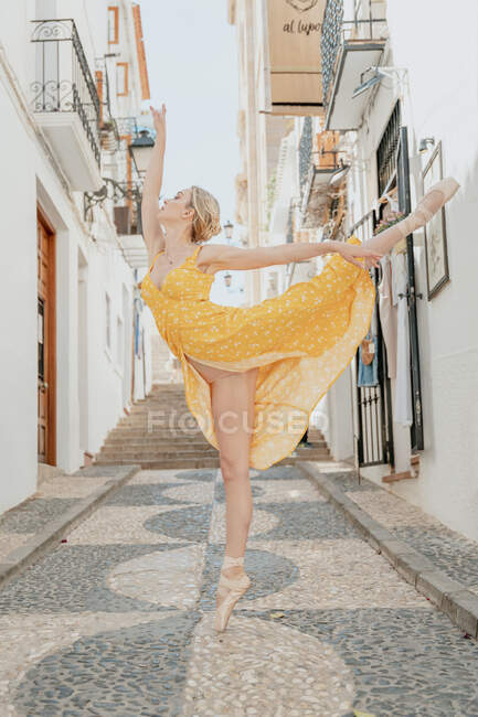 Full body of gorgeous female in pointe shoes performing graceful ballet movement with raised leg and arm — Stock Photo