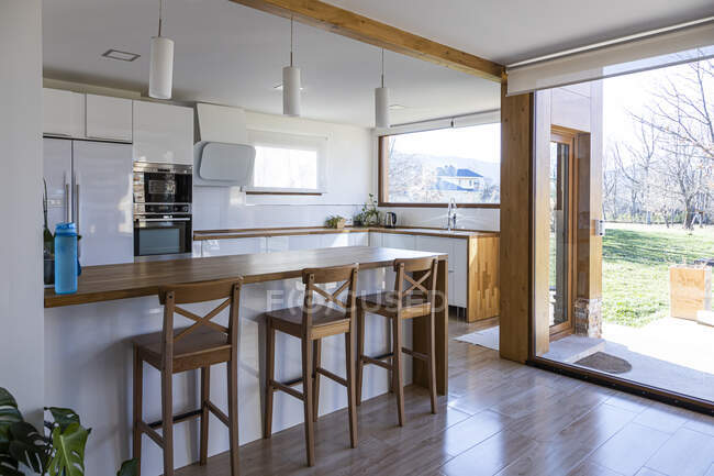 Esquina de la elegante cocina con paredes blancas y de ladrillo, suelo de madera, encimeras de madera - foto de stock