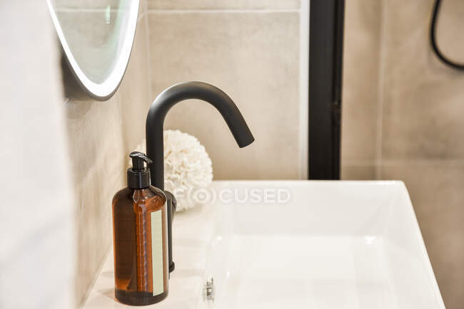 Nahaufnahme eines Waschbeckens mit modernem Wasserhahn und Zubehör wie Seife, Schwamm und Spiegel — Stockfoto