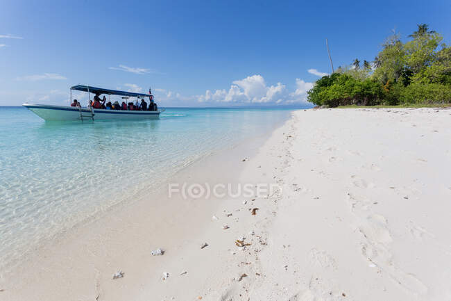 Bateau à moteur sur la mer azur clair transportant les voyageurs de la plage de sable fin dans la station tropicale ensoleillée de Malaisie — Photo de stock
