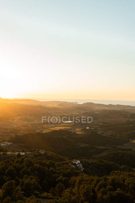 Paysage vue sur les monts et le champ agricole avec des arbres contre la mer avec horizon sous un ciel clair en soirée d'automne — Photo de stock
