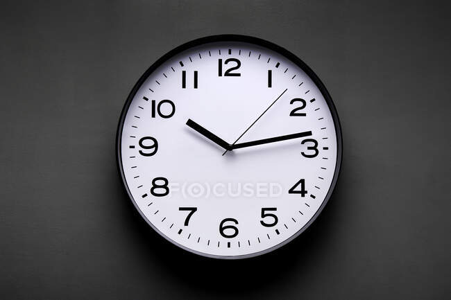Round shaped minimalistic clock with numbers and arrows on black background — Stock Photo