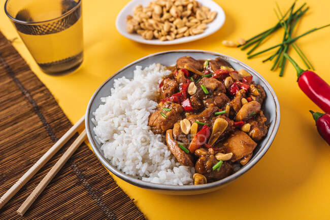 Du dessus bol de composition avec poulet kung pao avec arachide de riz blanc et piment rouge et oignon vert et baguettes — Photo de stock
