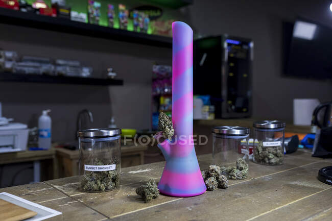 Creative design of bong and transparent containers with dried cannabis flower buds on table in room — Stock Photo