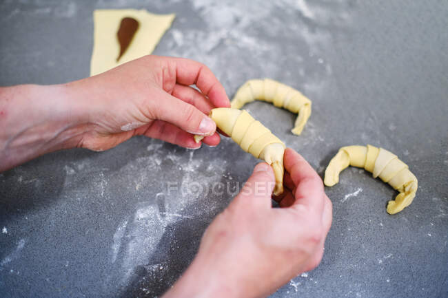 Hoher Winkel der Ernte unkenntlich Konditor Kochen hausgemachte kleine Croissants mit Schokolade auf grauem Tisch in der Küche — Stockfoto