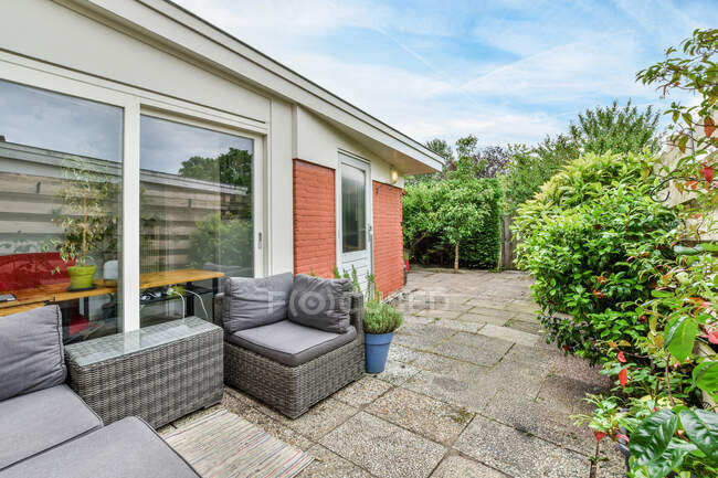 Amplia terraza con zona de estar y plantas verdes ubicadas cerca de casa residencial durante el día - foto de stock