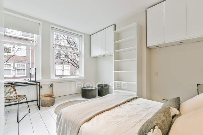Интерьер современной спальни с удобной кроватью и пустыми полками в новой квартире оформлен в минимальном стиле — стоковое фото