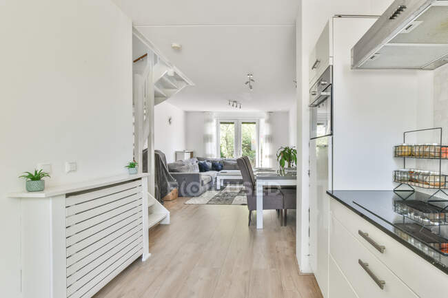 Інтер'єр сучасної квартири зі світлою кухнею і просторою вітальнею в мінімалістичному стилі вдень — стокове фото