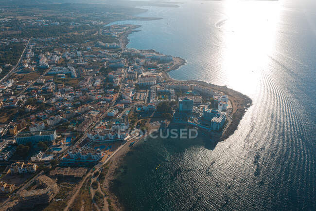 Vue par drone d'Ibiza avec bâtiments et rivage contre la mer ondulée éclairée par la lumière du soleil en Espagne — Photo de stock