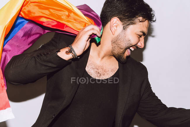 Crop excité barbu mâle riant avec la bouche ouverte et agitant drapeau multicolore symbole de fierté LGBTQ — Photo de stock