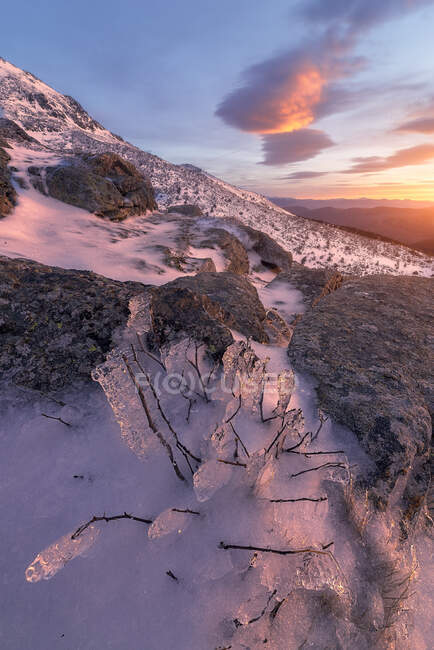 Malerische Landschaft von felsigen Bergen mit Schnee bedeckt unter bunten bewölkten Himmel bei Sonnenaufgang — Stockfoto