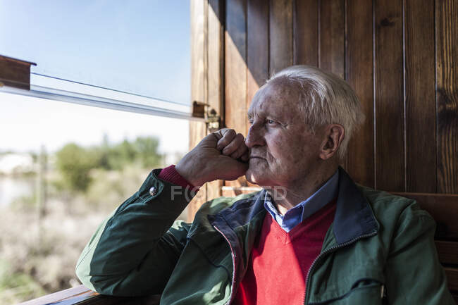 Side view of attractive man and old man traveling in an old wooden train carriage looking out the window — Stock Photo