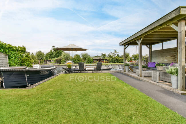 Vista panoramica di motoscafi ormeggiati sul fiume increspato tra prati in giardino con divano sotto tetto e ombrellone nella provincia di Utrecht Paesi Bassi — Foto stock