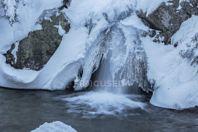 Long exposure of fast waterfall flowing through snowy terrain in Sierra de Guadarrama National Park — Stock Photo