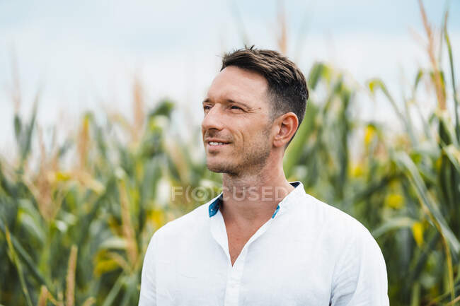 Adult bearded male with brown hair in casual wear looking away under light sky — Stock Photo