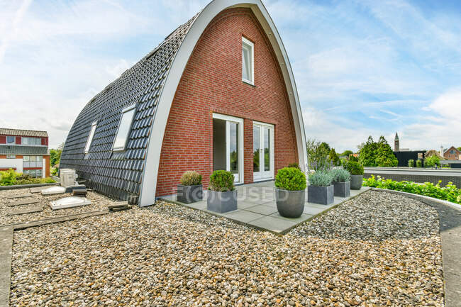 Kreative Gestaltung von gewölbten Gebäudeflächen mit Ziegeldach gegen Pflanzen unter bewölktem Himmel in der Provinz Utrecht Holland — Stockfoto