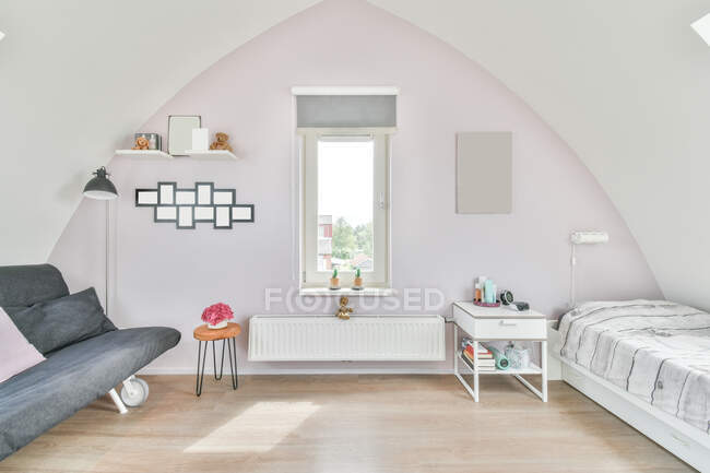 Design criativo de quarto de crianças com janela entre sofá e cama em parquet em casa à luz do sol — Fotografia de Stock
