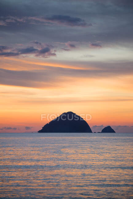 Silhouette of hill washed by rippling sea under colorful sundown sky and clouds in Malaysia — Stock Photo