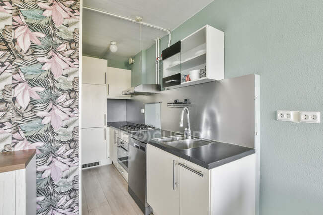 Interior da pequena cozinha moderna com mobiliário branco e aparelhos modernos em novo apartamento — Fotografia de Stock