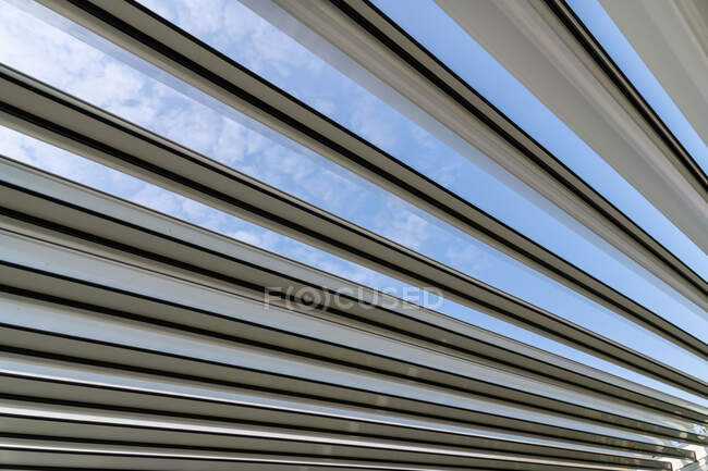Низький кут стелі сучасного будинку з металевими панелями і скляними деталями під яскраво-блакитним небом в сонячний день — стокове фото