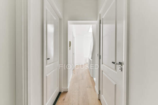 Interior del pasillo con puertas blancas en casa grande moderna con suelo de parquet - foto de stock