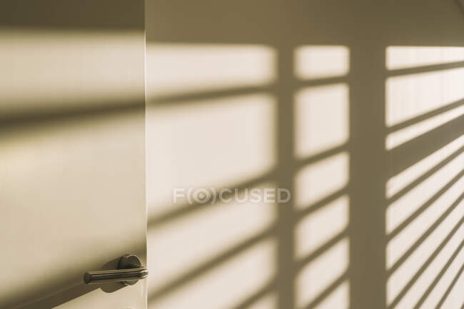 Інтер'єр дверної ручки в порожньому просторому лофт-холі з геометричними тінями і сонячним світлом на білих стінах — стокове фото