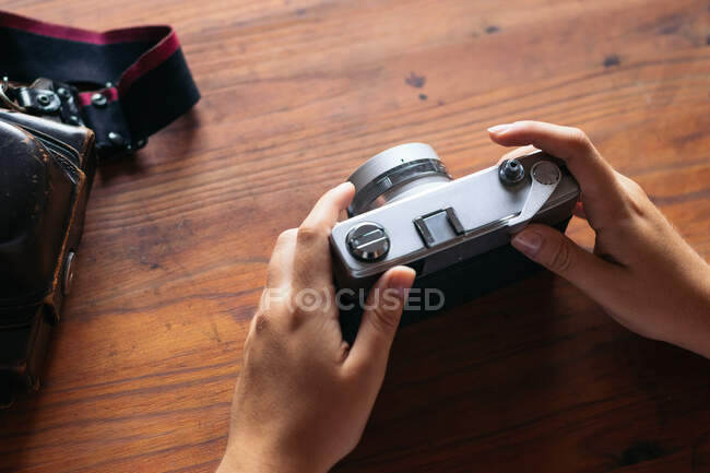 Top view of crop anonymous person with vintage photo camera and leather case on wooden desk — Stock Photo