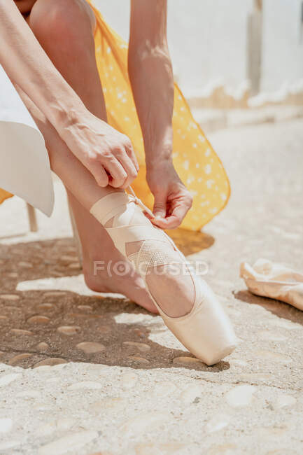 Cortar bailarina irreconhecível vestindo vestido longo e sapato pontiagudo sentado na cadeira na rua — Fotografia de Stock