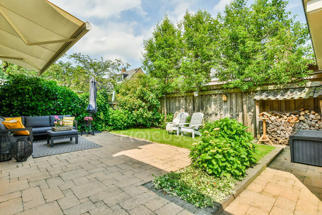 Terrasse du chalet résidentiel avec canapé confortable dans le coin salon et plantes vertes dans la journée ensoleillée — Photo de stock
