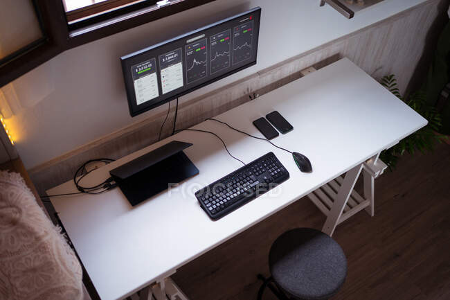 Сверху дисплей с ценовой динамикой графиков криптовалют над таблицей с клавиатурой ноутбука и смартфона — стоковое фото