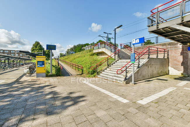Паркування для велосипедів, розташованих біля сходів, що ведуть до залізничної платформи в місті в сонячний день. — стокове фото