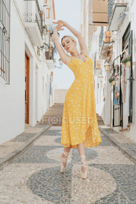 Corpo inteiro de linda fêmea em sapatos pontiagudos realizando movimento de balé gracioso com braços levantados — Fotografia de Stock