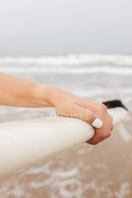 Crop unrecognizable female athlete with surfboard in daylight — Stock Photo