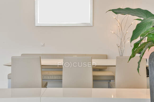 Творчий дизайн їдальні з декоративною лампою на столі між стільцями і лавками вдома — стокове фото